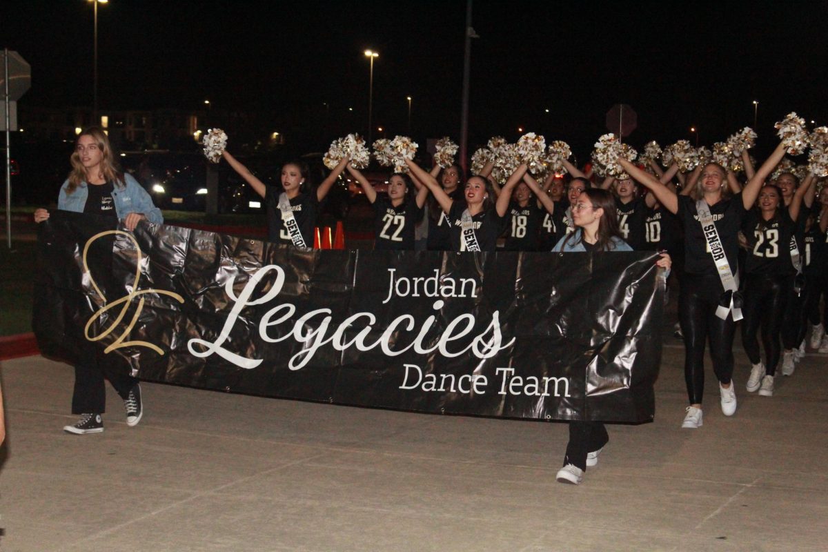 Legacies follow behind the cheerleaders, their seniors leading the pack. They perform a perfectly-synchronized pom routine. 