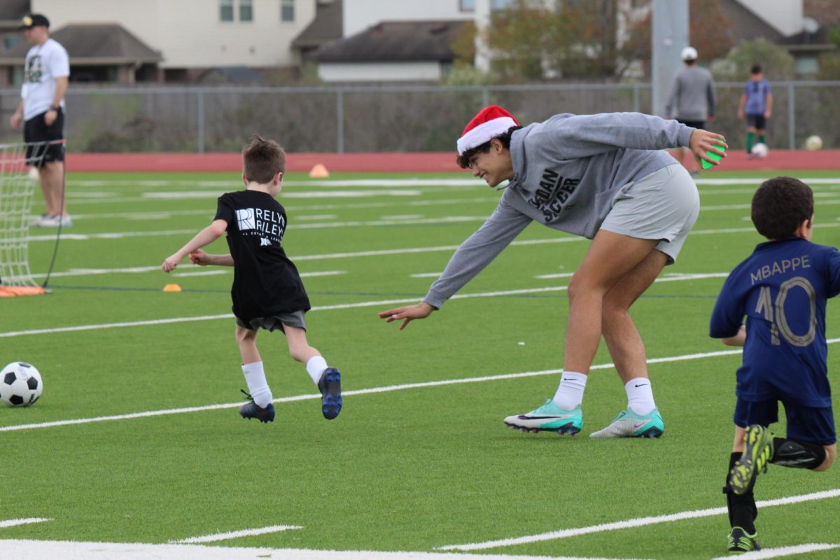 Senior varsity player Gabriel Diniz plays soccer-tag with a player attending Jordans Future Warriors Kids Camp. Players with Jordans soccer program were designated as coaches, leading kids through numerous activities and drills in a fun manner. 