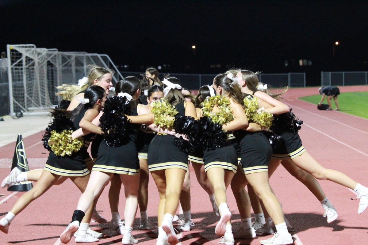 Freshmen cheerleaders perform a cheer while in a team huddle. The cheerleaders chanted to boost the crowd and football team’s spirits. 

