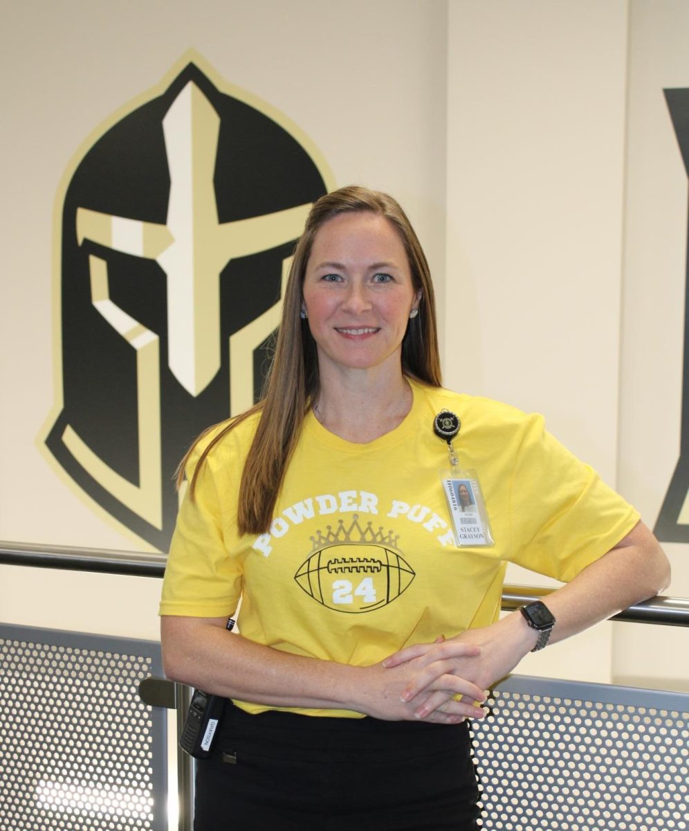 Stacey Grayson poses for a picture in front of the School Logo.